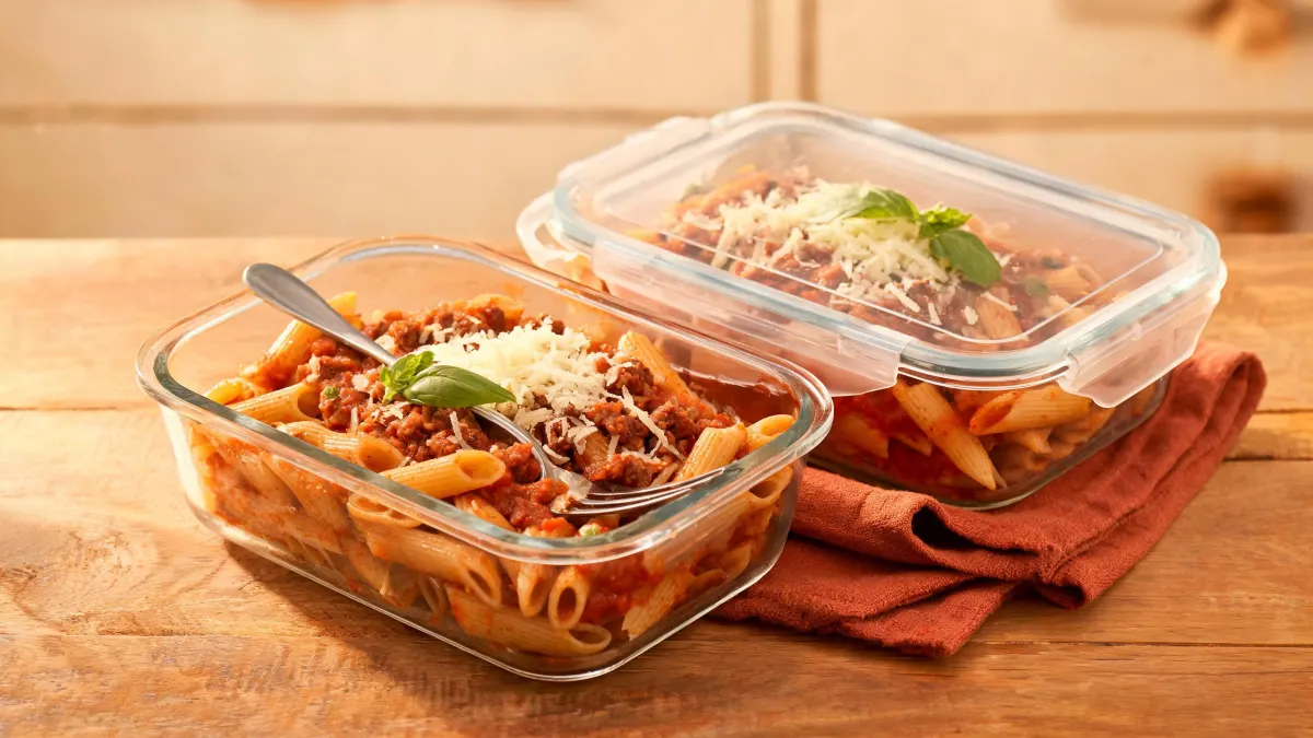 Illustratie van meal prep bakjes met volkoren penne in tomatensaus met gehakt en geraspte kaas
